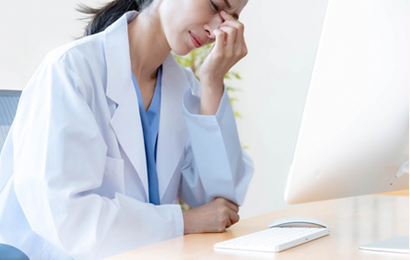 眉間を抑える白衣を着た女性